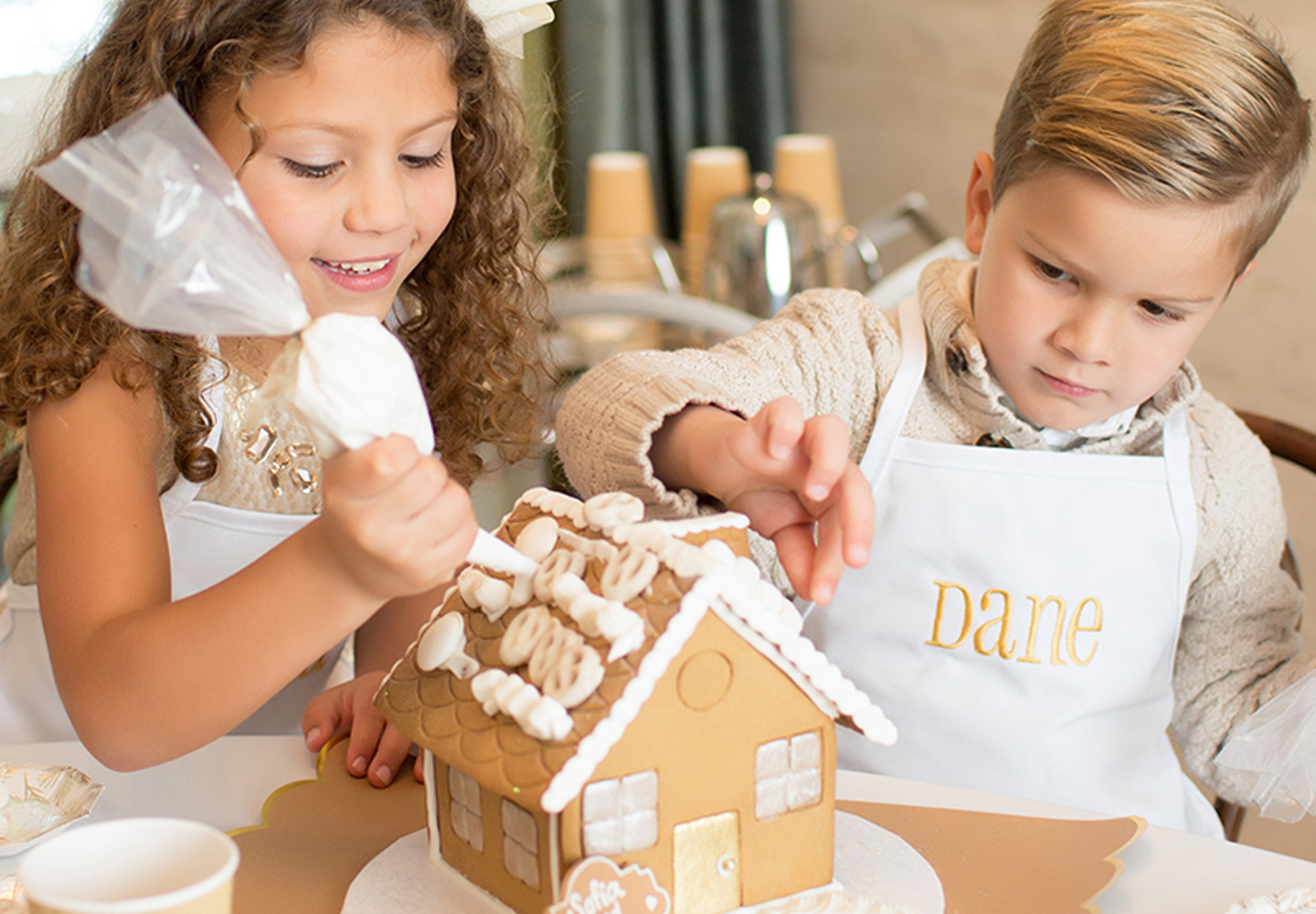 Two kids decorating a gingerbread house.