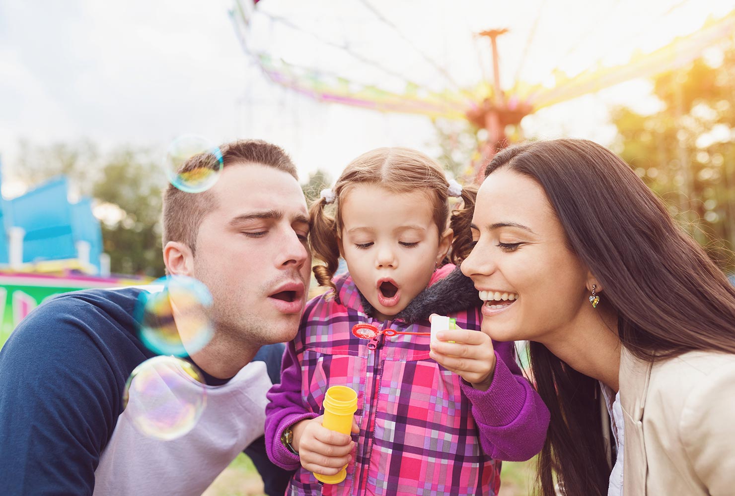 young girl blowing bubbles with her parents