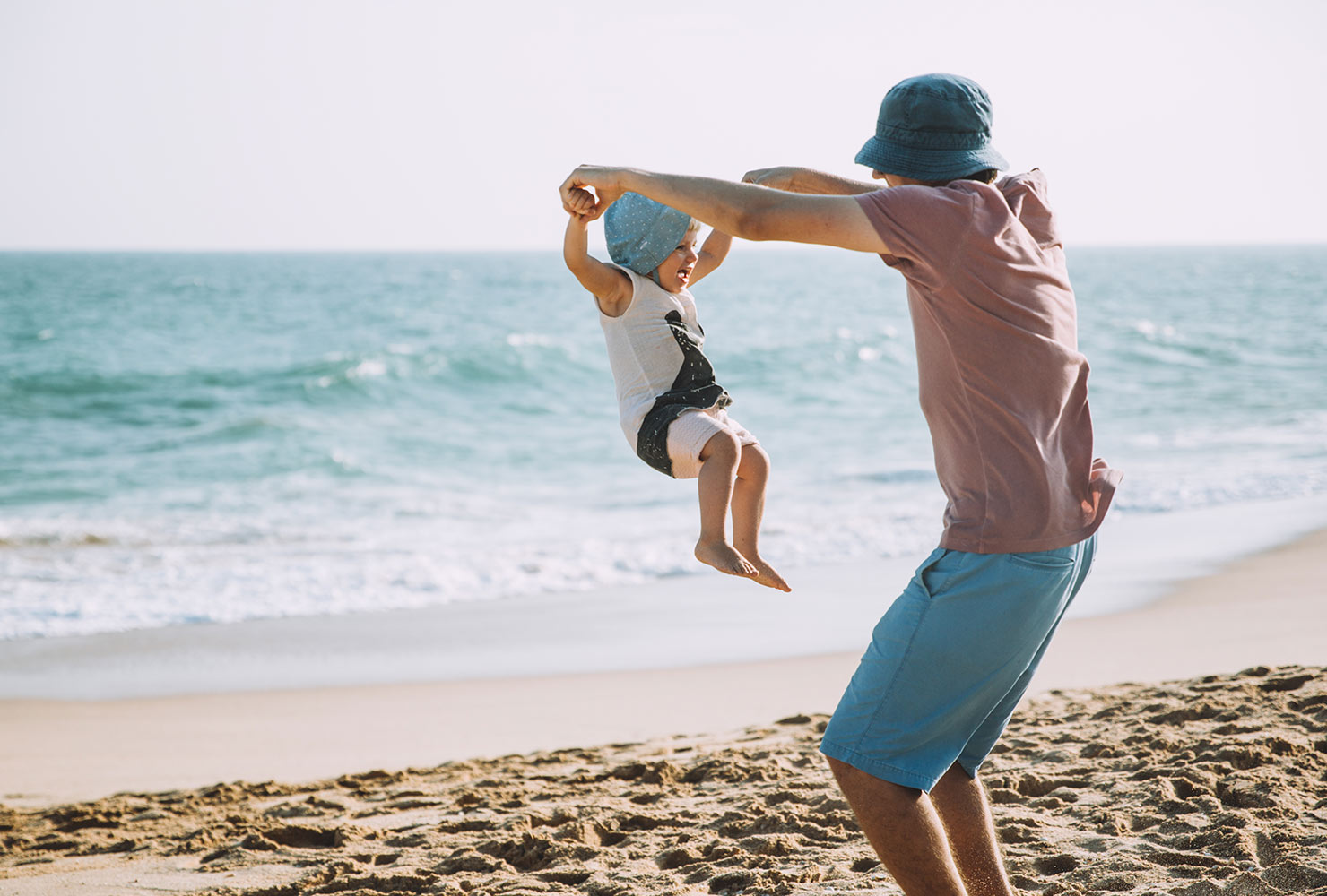 dad playing with baby at the beach