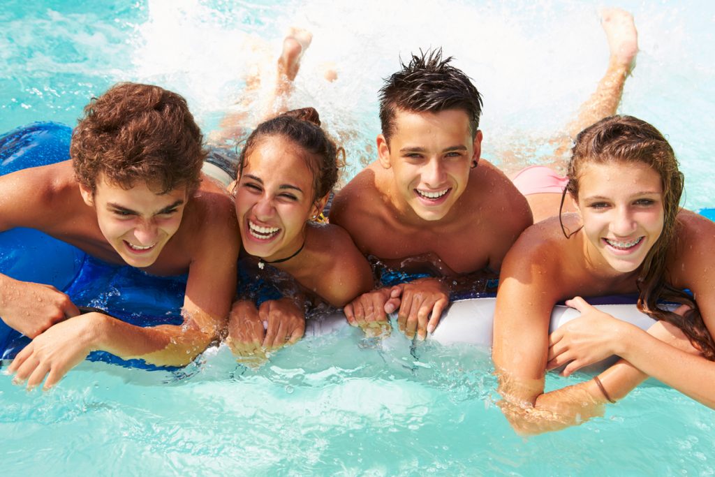 Group Of Teenage Friends Having Fun In Swimming Pool for a birthday party.