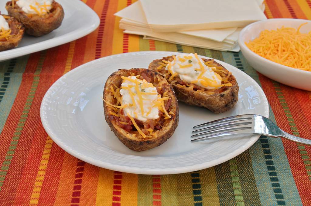 Rustic baked potato skins stuffed with bacon and cheese and topped with sour cream.