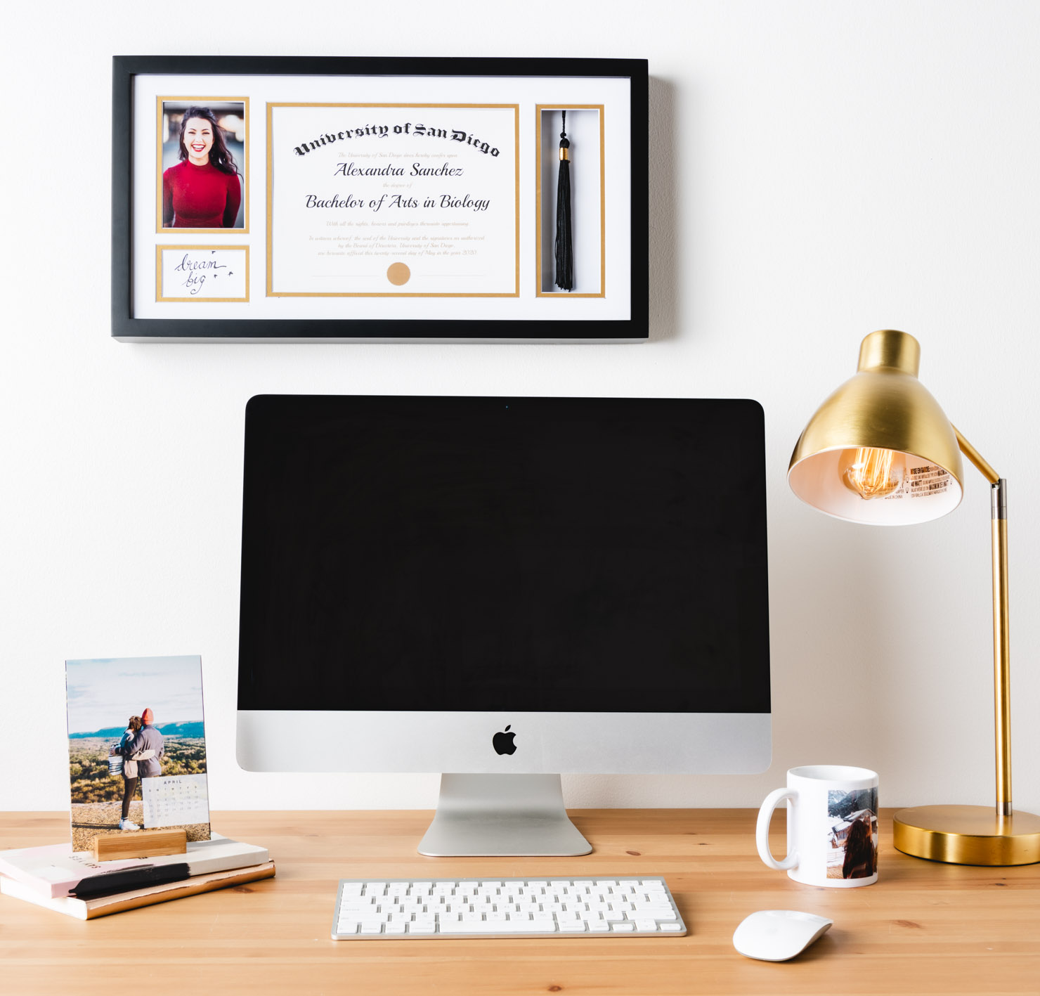 computer on desk with diploma above it 
