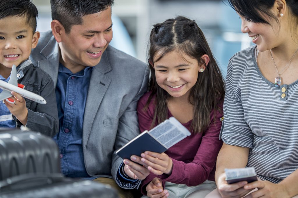 A family is at an airport getting ready for their fun family summer vacation ideas.