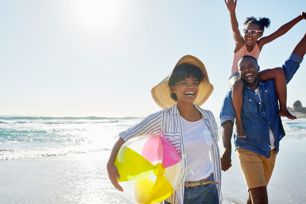 Shot of an adorable little girl going for a walk with her parents on the beach during their summer vacation