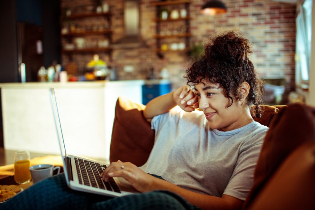 Close up of a young woman using a laptop at home to watch videos.