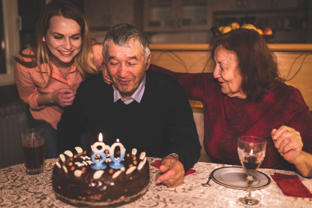Grandfather celebrating his 80th birthday with his family at a restaurant. 