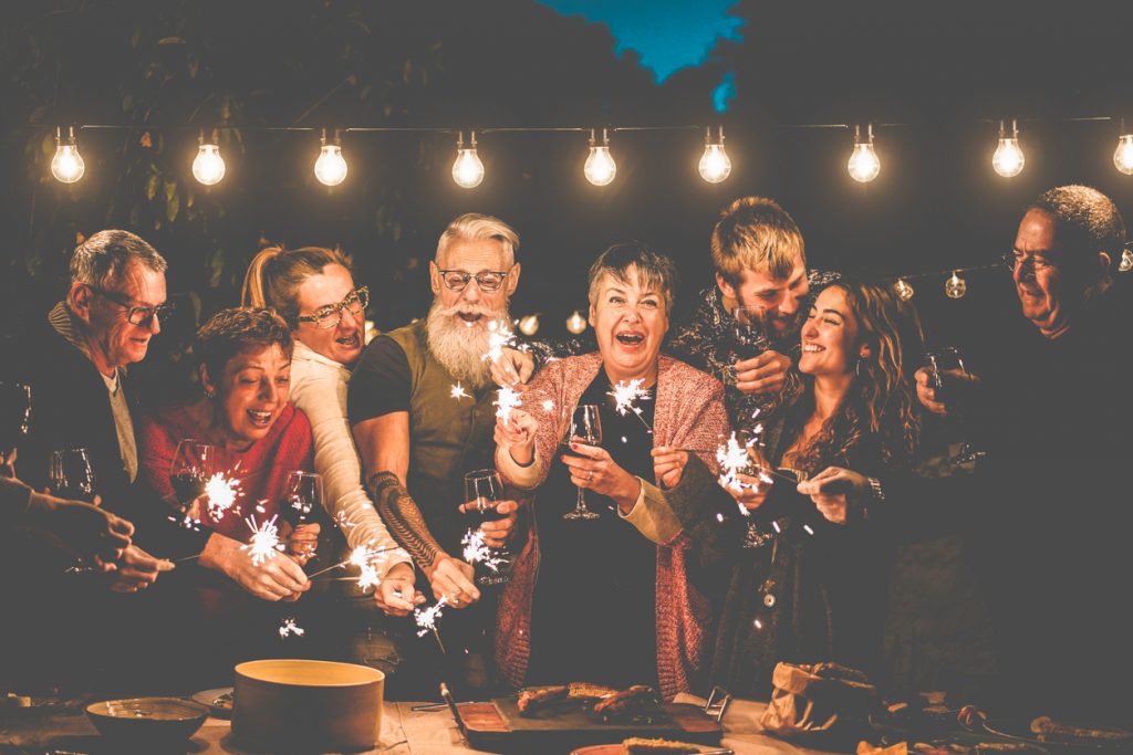 Happy family and friends celebrating a birthday party with sparkler fireworks after dinner.