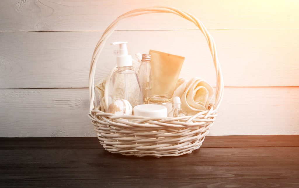 Wicker basket with spa treatments on wooden table.