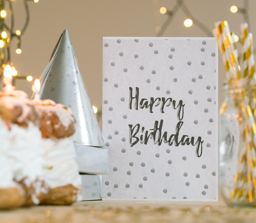 Birthday card lying on table with golden decoration.
