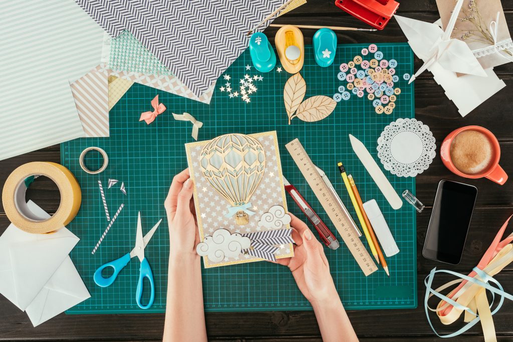 Cropped image of a woman holding scrapbooking postcard with a wooden balloon.