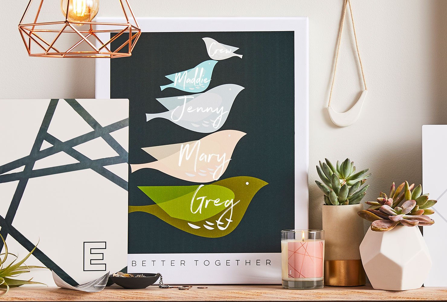 Frame with birds and different family names on a bedroom shelf.