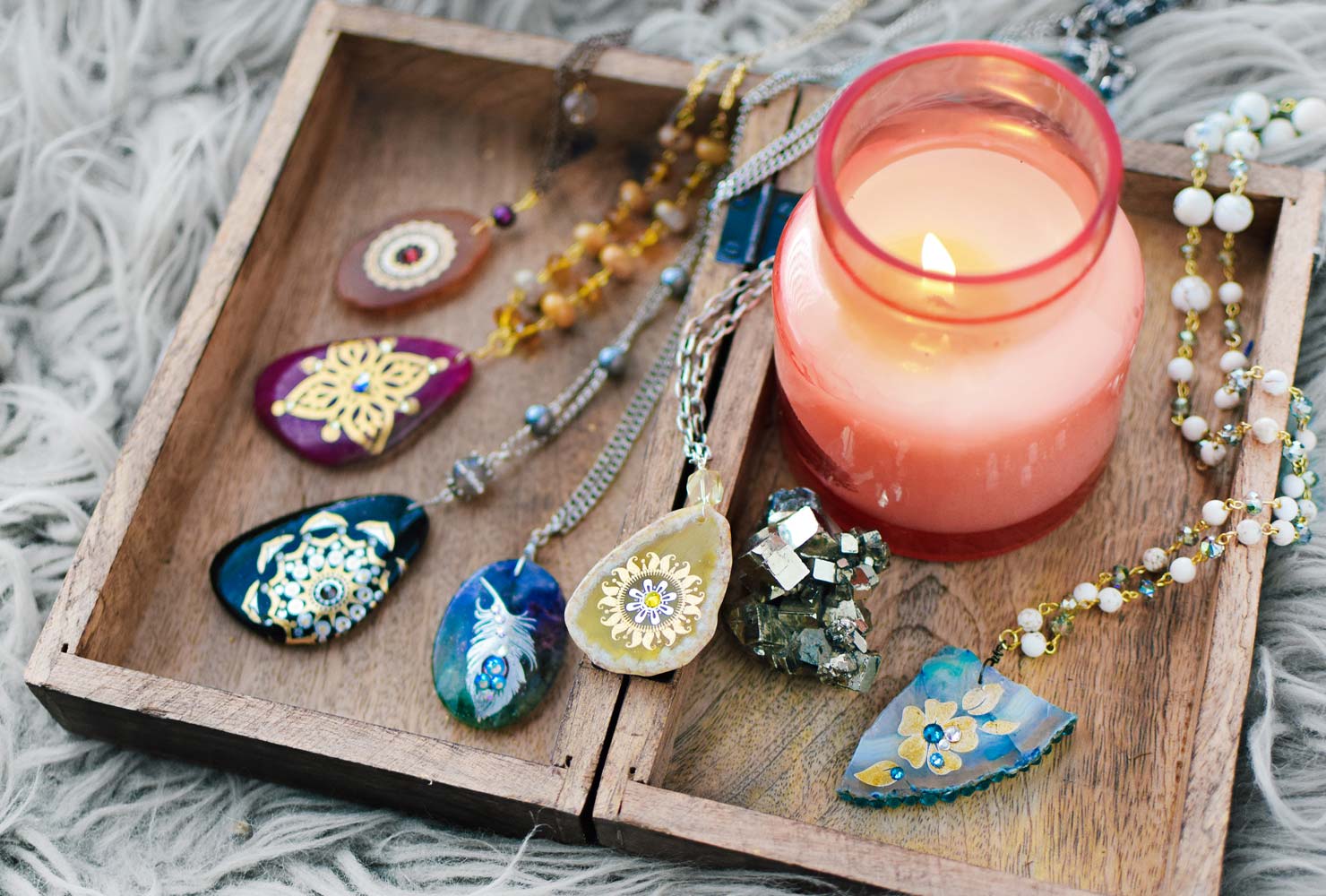 Boho necklaces and pink candle.