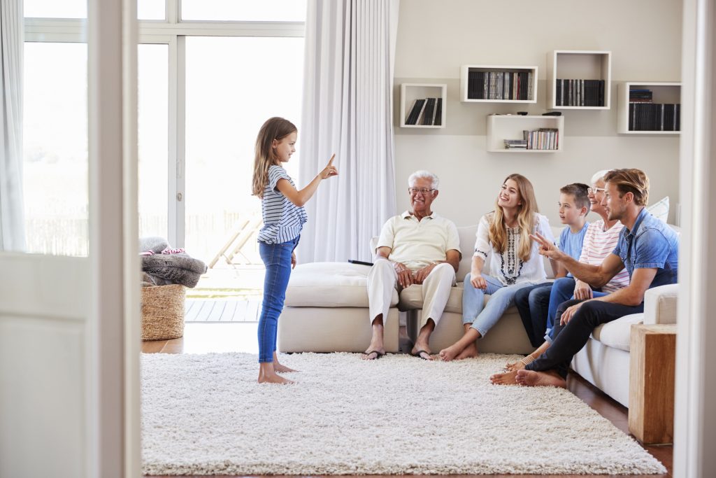 Family Sitting On Sofa At Home Playing Charades