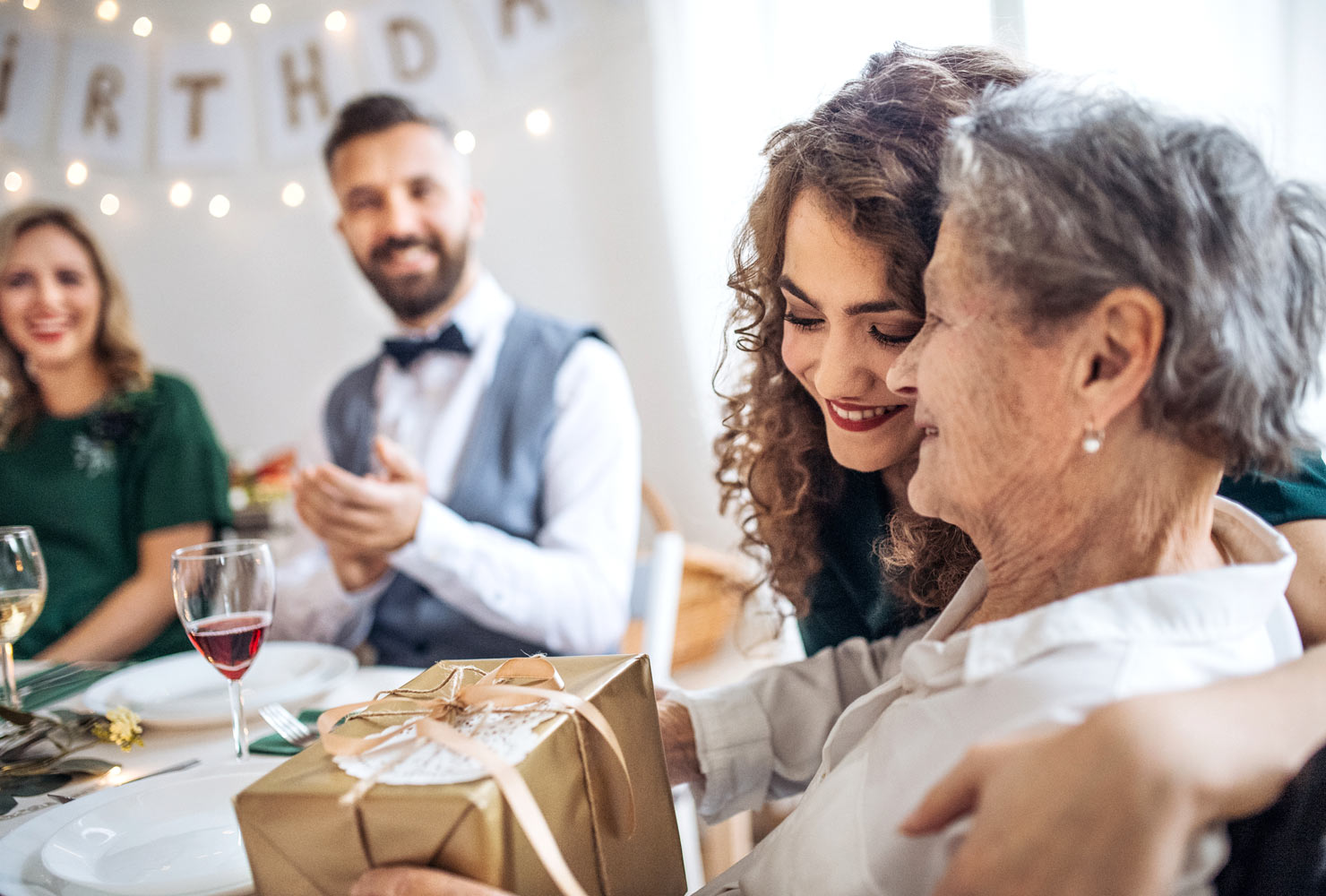 Young woman hugging an elderly woman with a gift