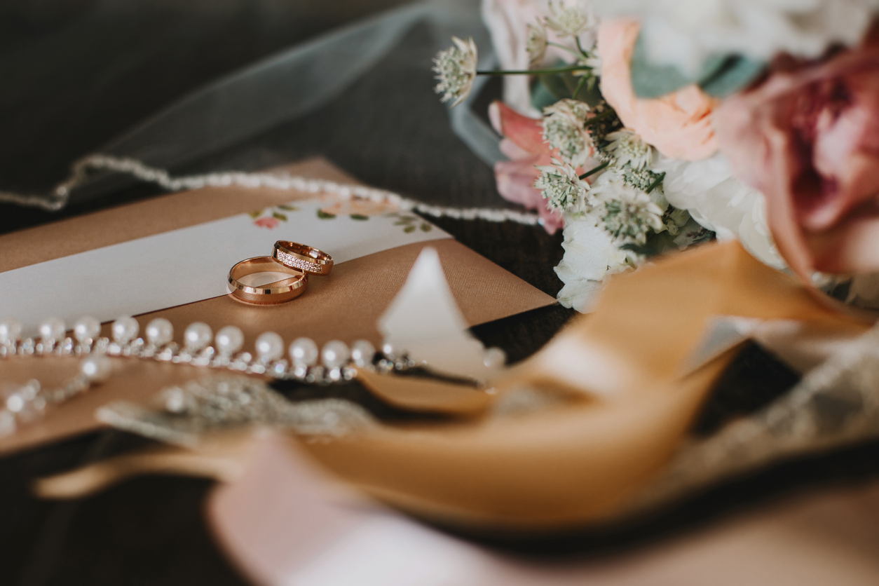 Two gold wedding rings with gemstones are among the accessories: bridal bouquet, cards, veils and lace ribbons.